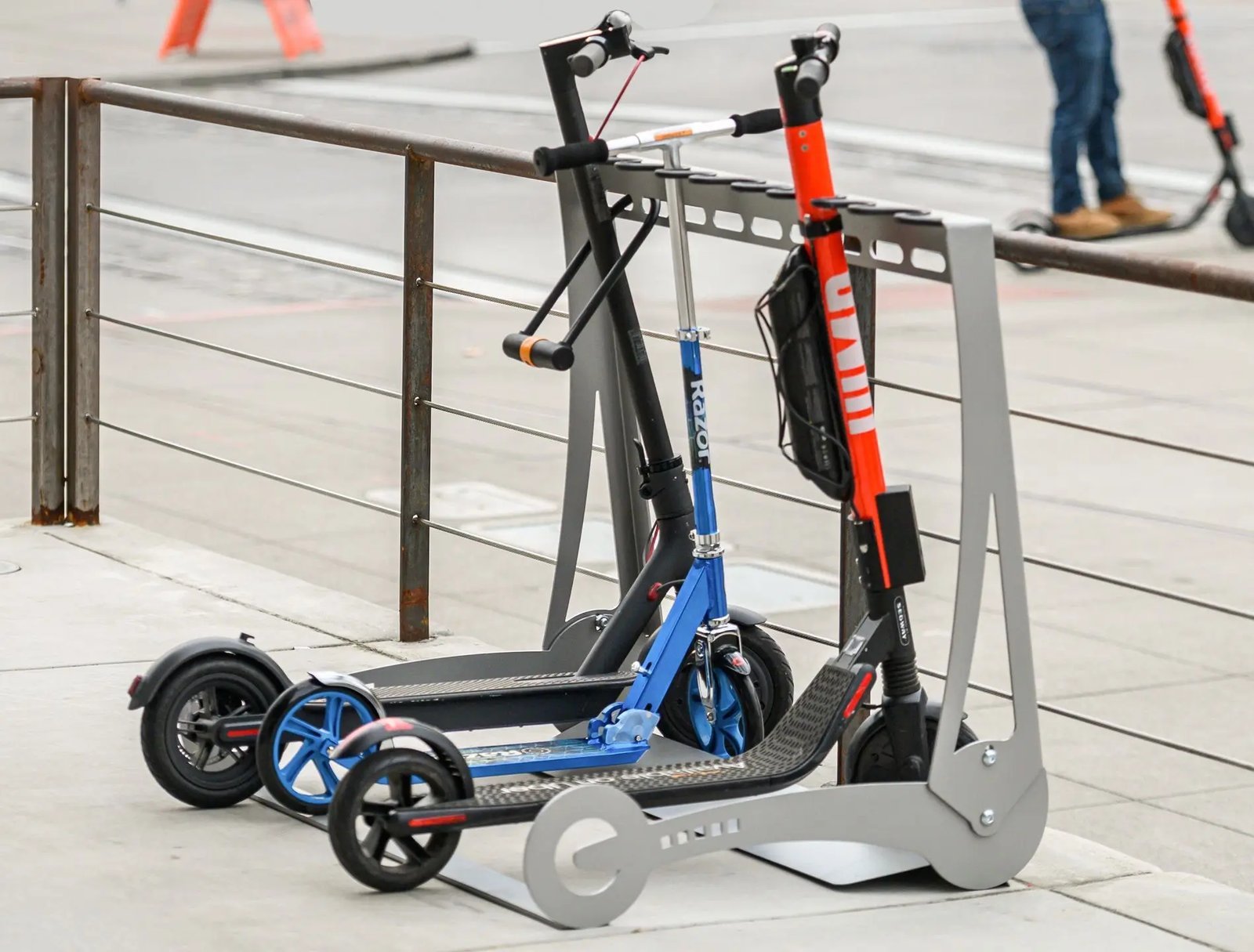 A kick scooter parked beside a rack with keys resting on the deck.