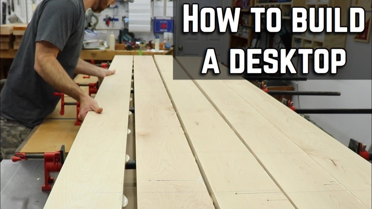 Essential tools and lumber for building a custom wooden desktop on a workbench.
