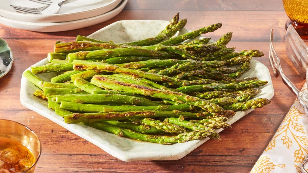 A home cook prepares fresh asparagus in a bright, modern kitchen setting.