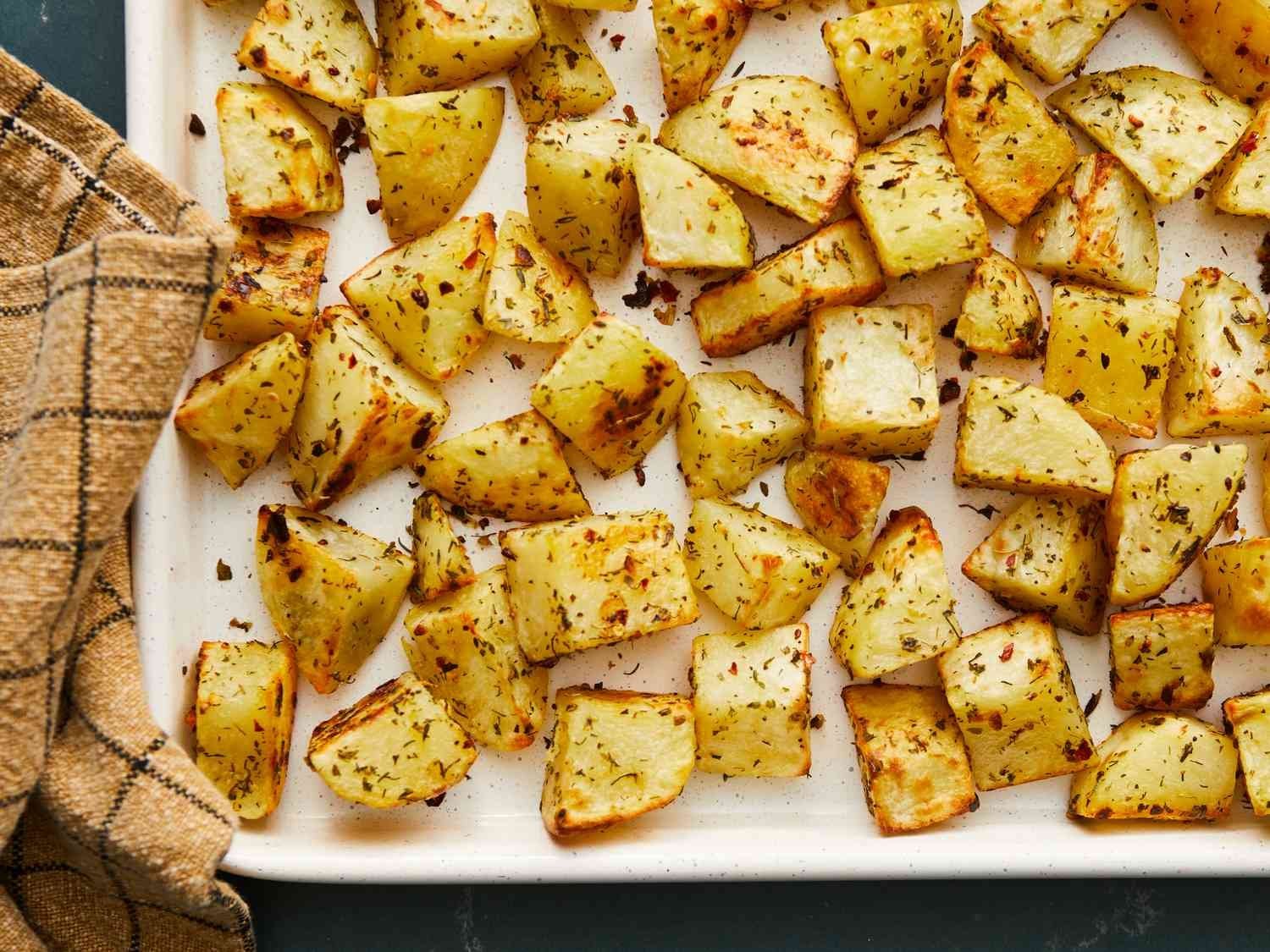 Fresh raw Yukon Gold and Russet potatoes prepared for roasting on a marble surface.