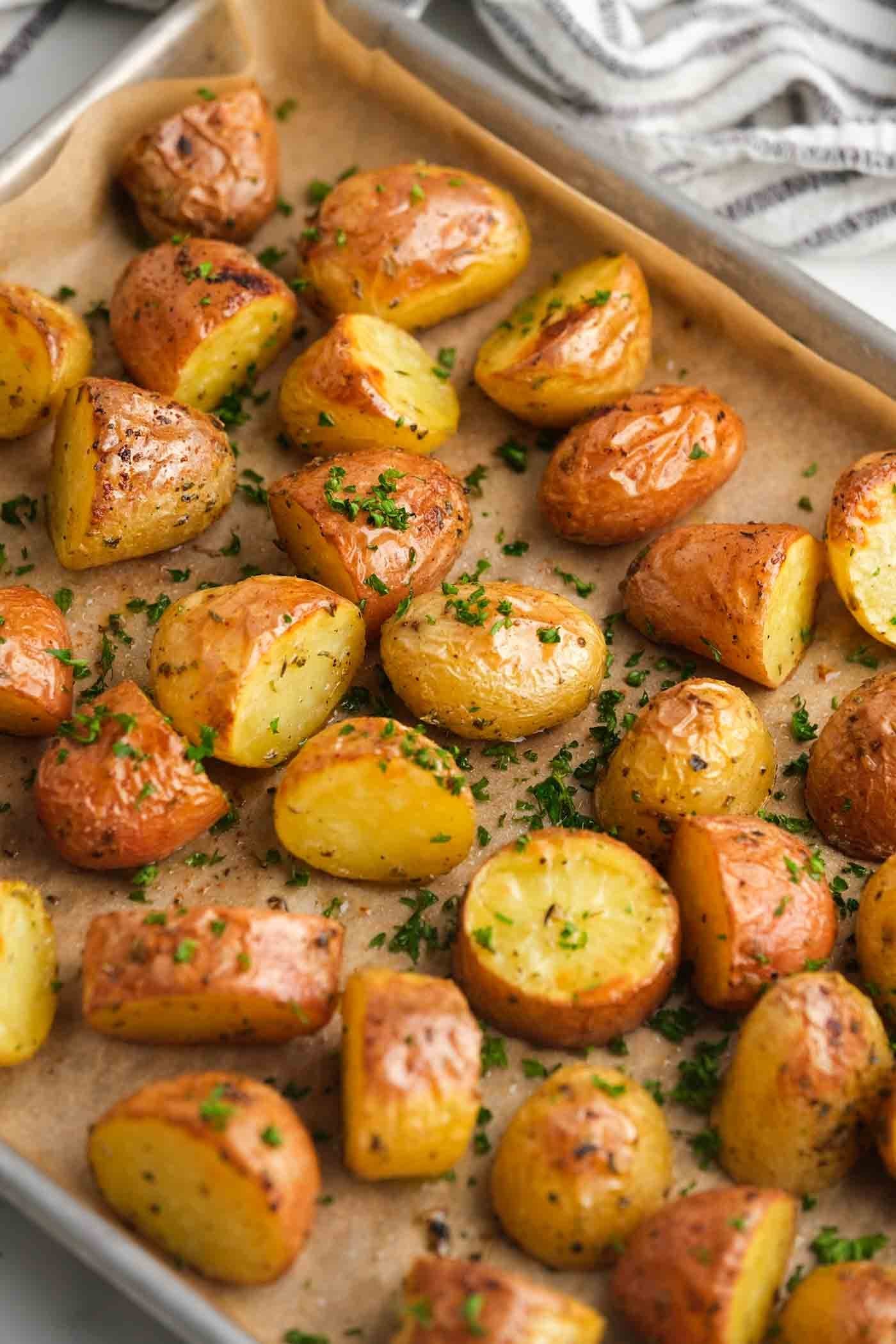 A delicious serving of oven roasted potatoes presented in a white stoneware bowl.