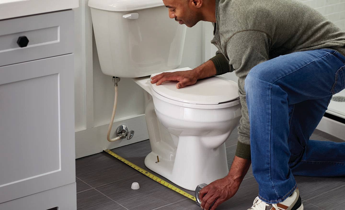 Close up of hands tightening hardware to fix a loose toilet seat.