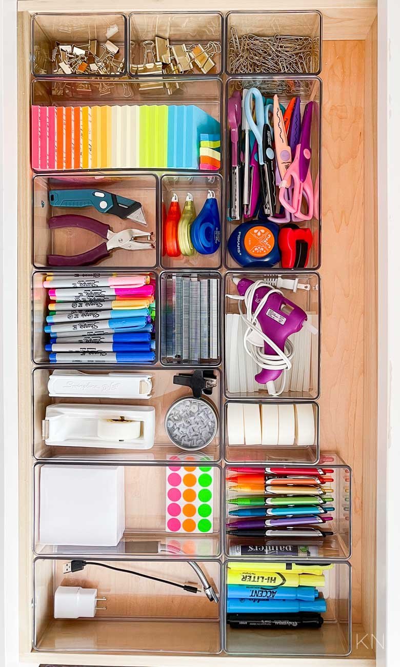 A calendar with a reminder note near an organized office supply cabinet.