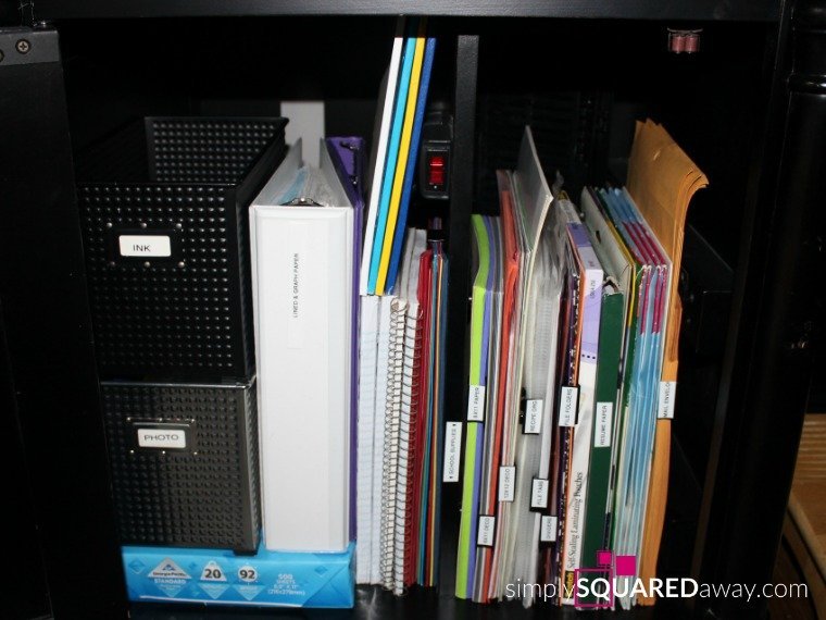 A perfectly organized office supply cabinet with clear plastic bins and minimalist labels.