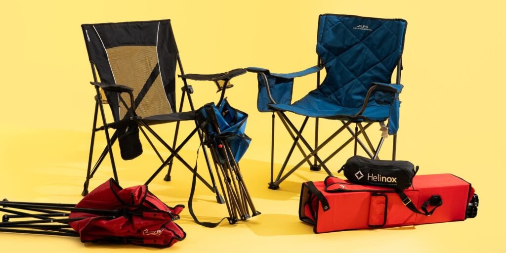 A person carefully putting a folding chair into a bag outdoors.