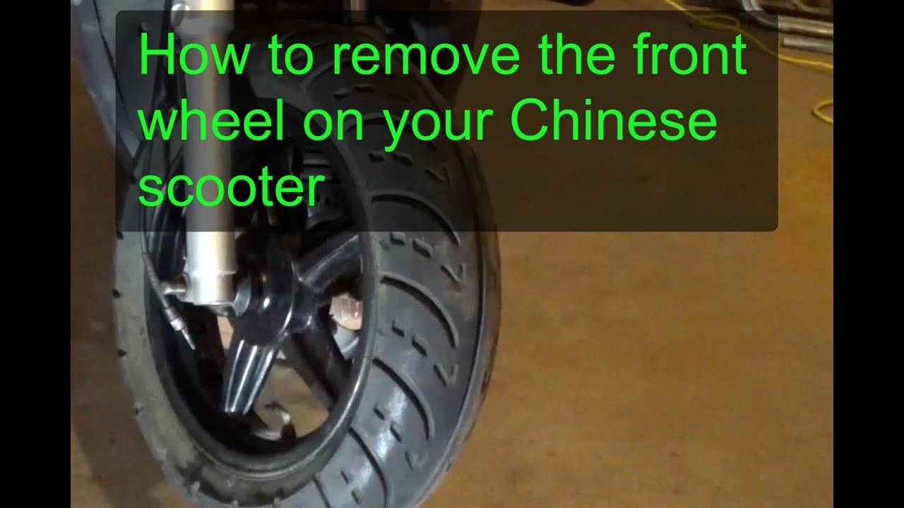 A scooter front fork with the wheel removed and hardware organized in a dish.