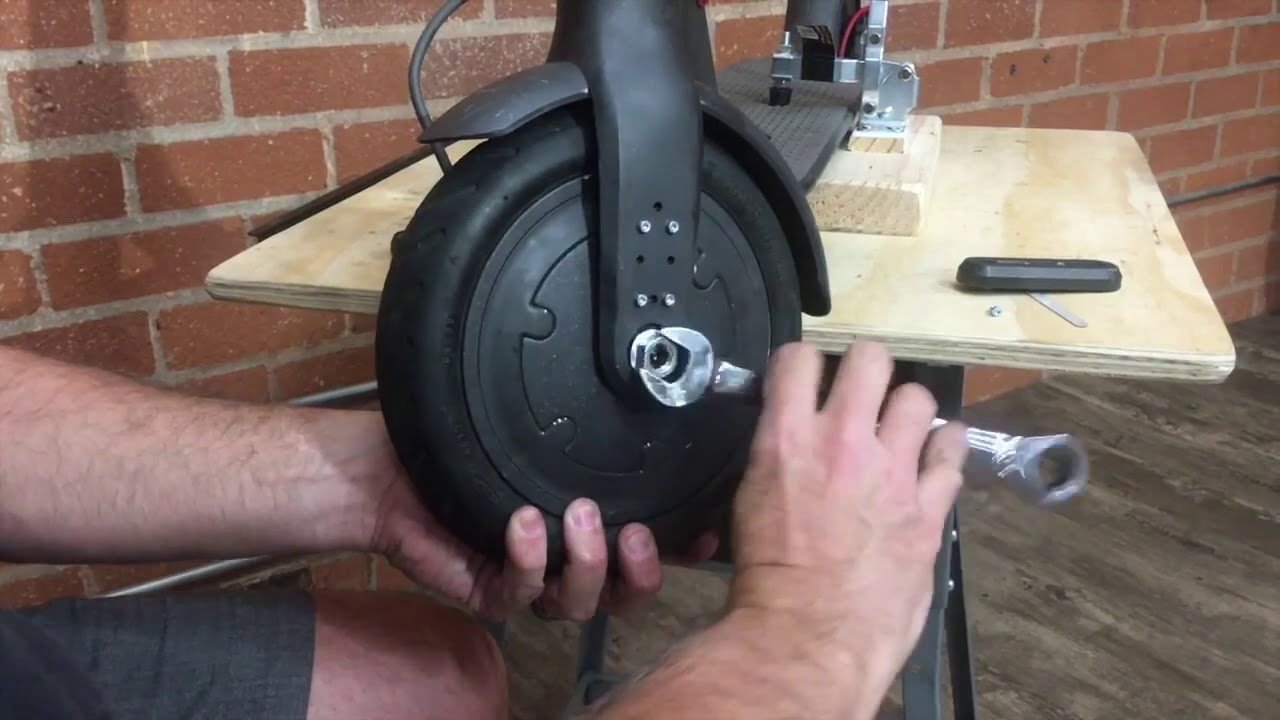 Technician checking the front fork of a scooter after wheel removal maintenance.