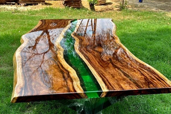 An artisan inspects a wooden dining table with an epoxy resin river inlay.