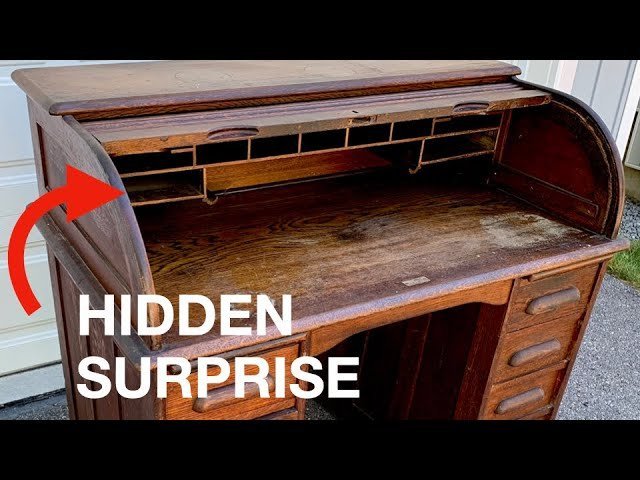 Closing a roll top desk carefully using the center handle for balance.
