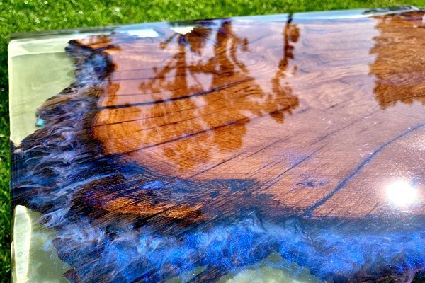 A close-up of porous oak wood being prepared for an epoxy resin table coating.