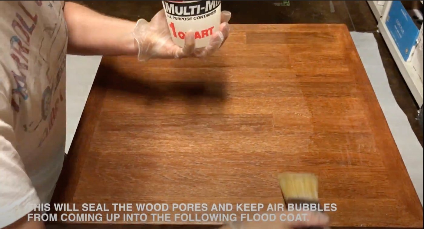 Applying a smooth layer of resin to a tabletop using a foam brush.