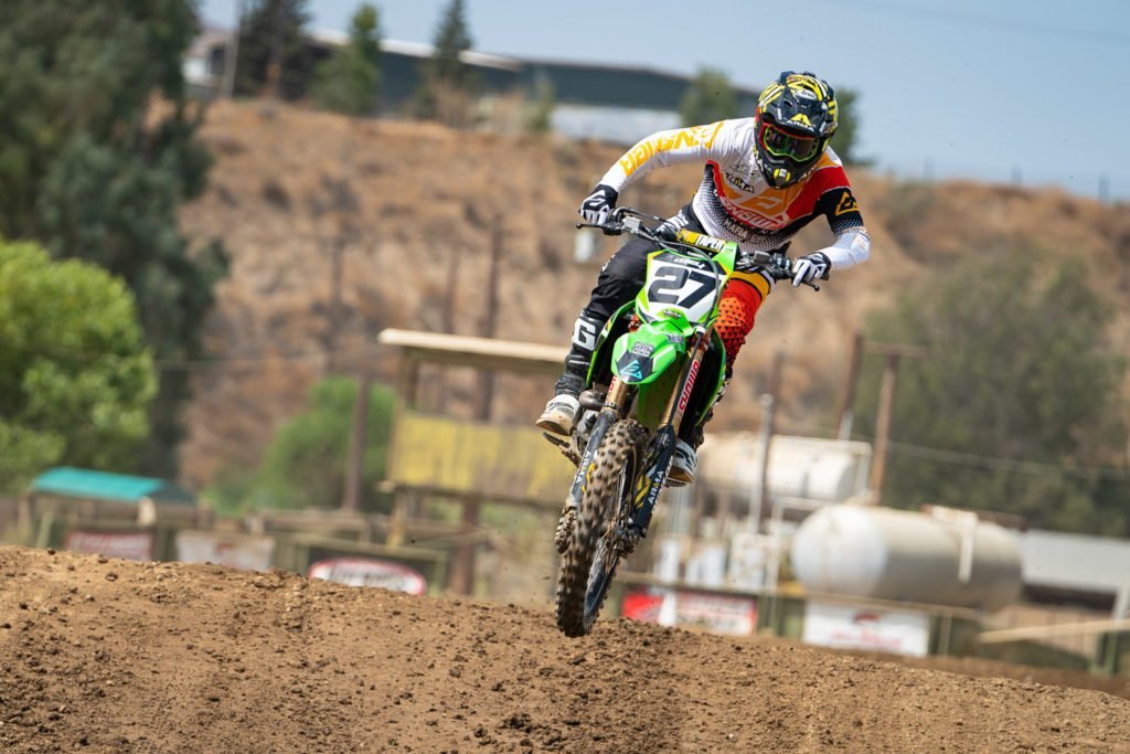 Mechanic adjusting the rear shock clickers on a dirt bike for better suspension performance.