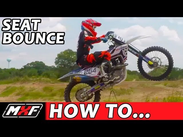 A motocross rider executes a perfect seat bounce on a dirt bike jump.