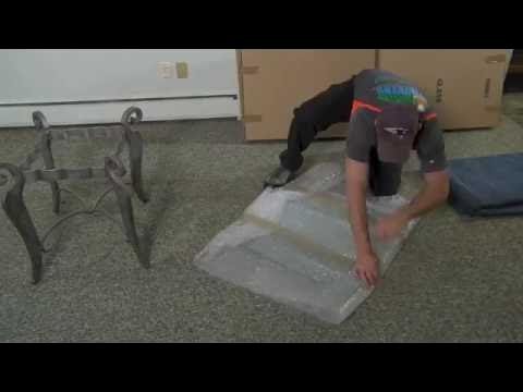 Two people moving a wrapped glass tabletop using a furniture dolly.