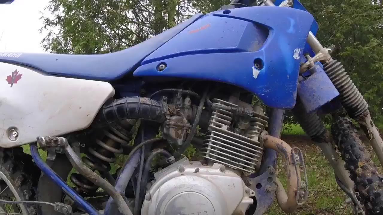 Using a socket wrench to remove a fouled spark plug from a motorcycle.