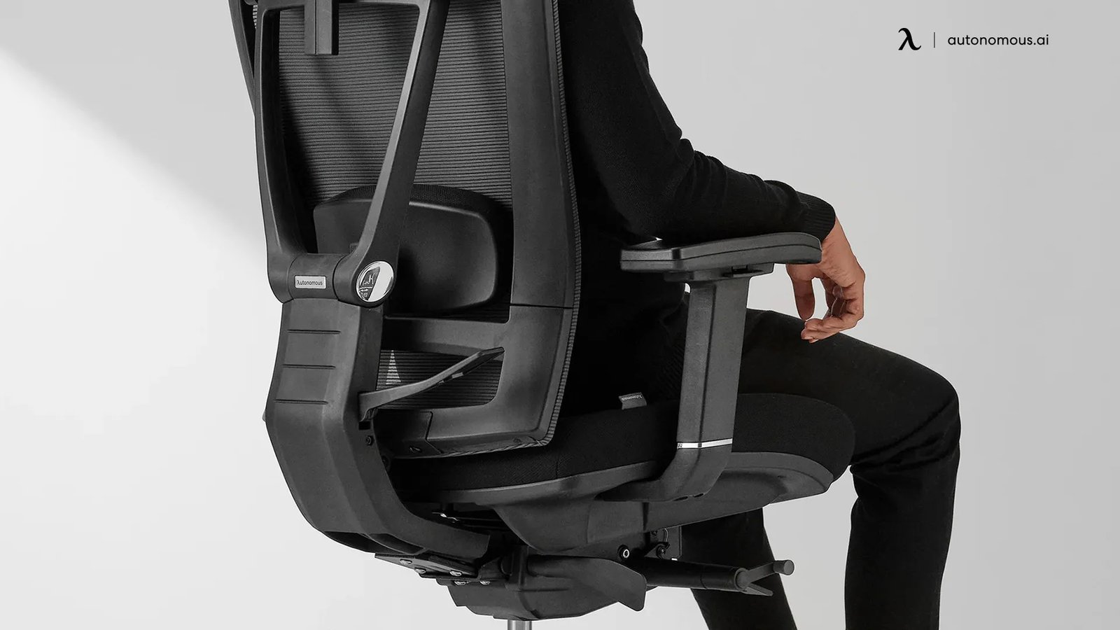 A person adjusting the lumbar support pad on an ergonomic office chair.