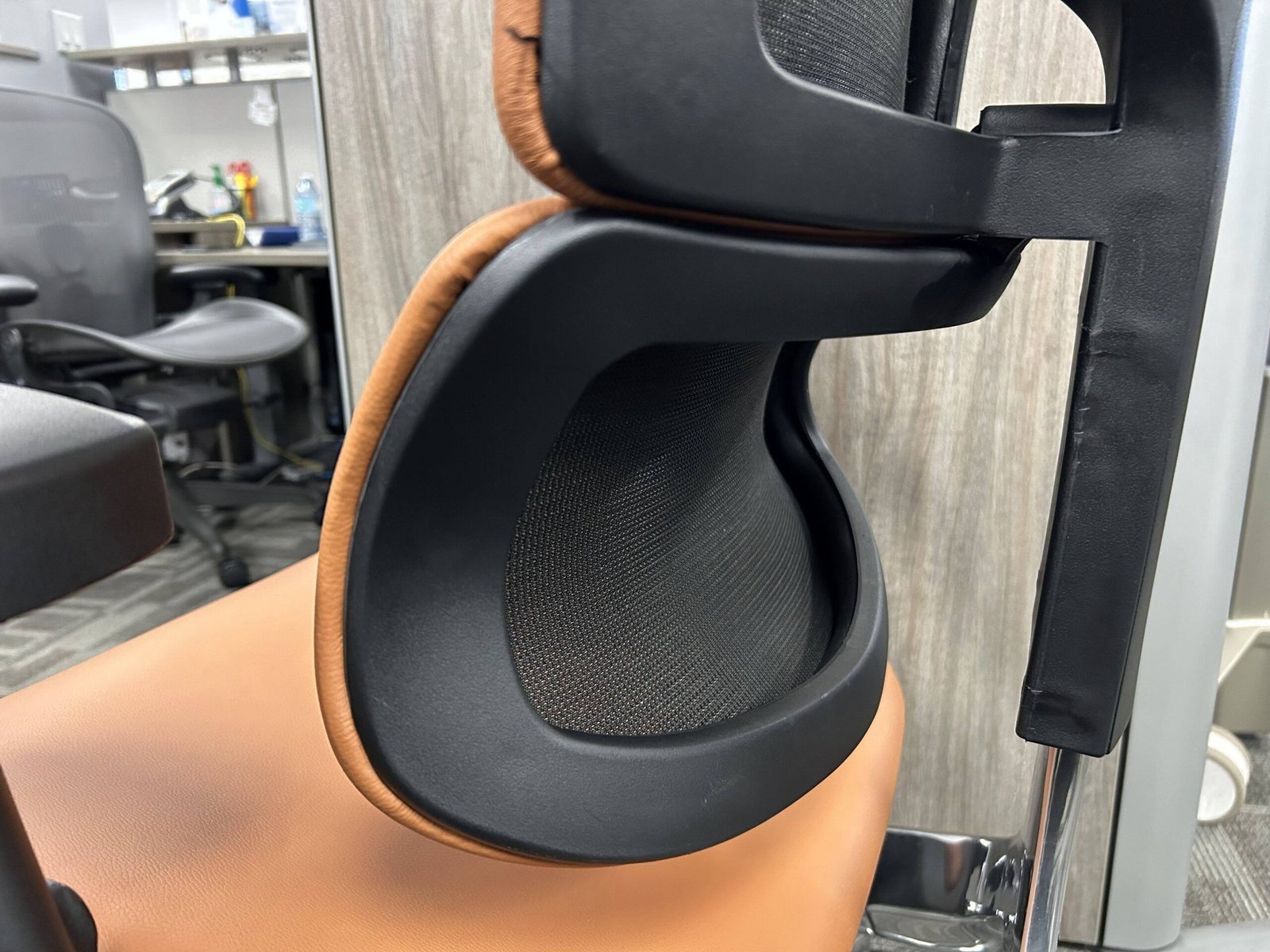 A person testing the lumbar support fit with their hand behind their back.