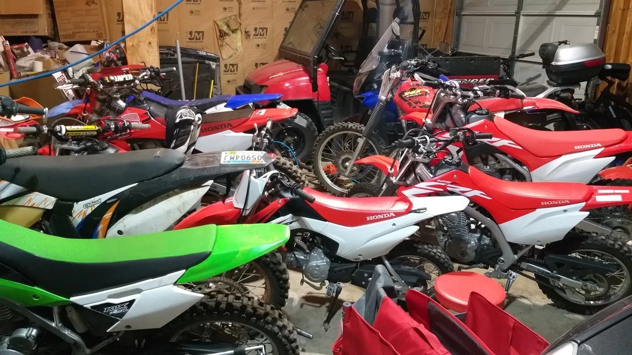 A dirt bike on a stand with a green battery maintainer light showing.