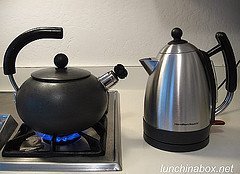 A modern electric kettle and a traditional stovetop kettle side by side on a counter.