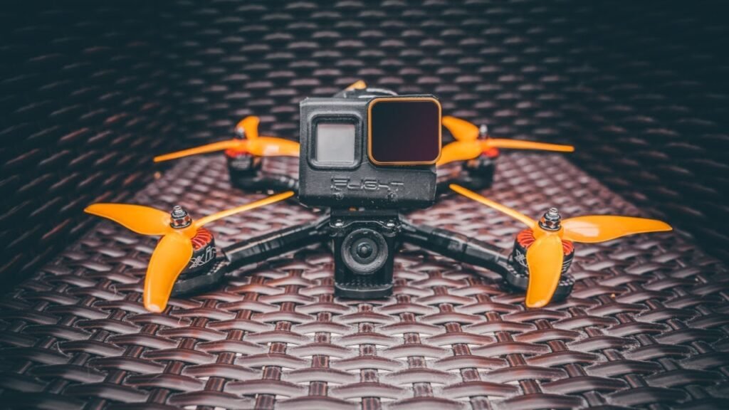 A modern FPV drone with goggles and controller sitting on a concrete surface.