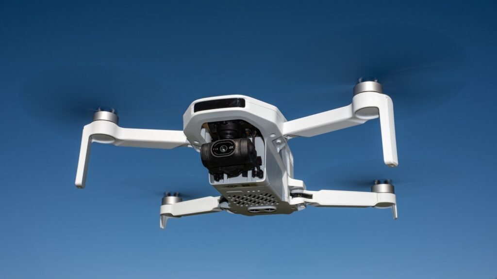A Potensic Atom 2 drone rests on a wooden table in a sunny field.