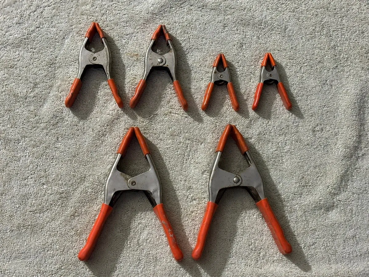 Small precision pliers and large heavy-duty pliers compared on a concrete table.