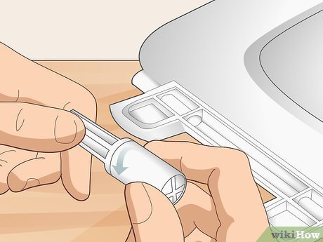 Cleaning a toilet seat hinge with a soft cloth.