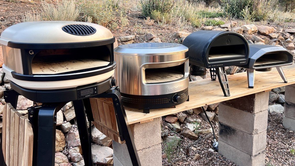 Two different models of high-quality pizza ovens placed on a clean patio.