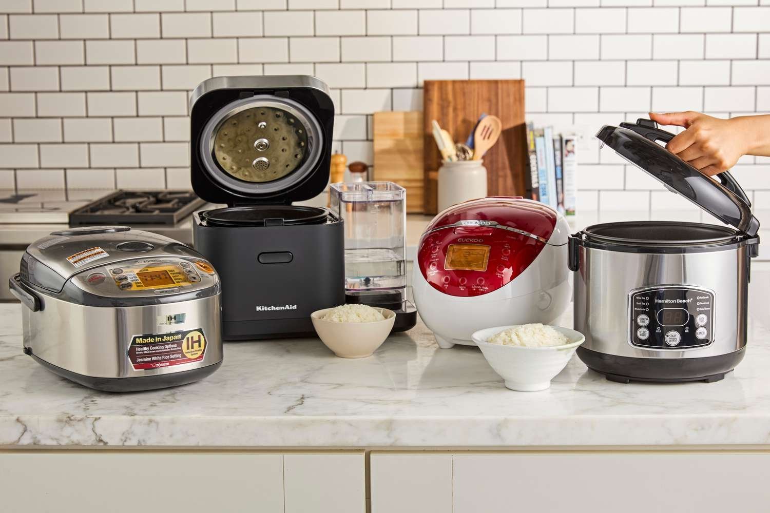 Three different premium slow cooker brands displayed on a wooden kitchen island.