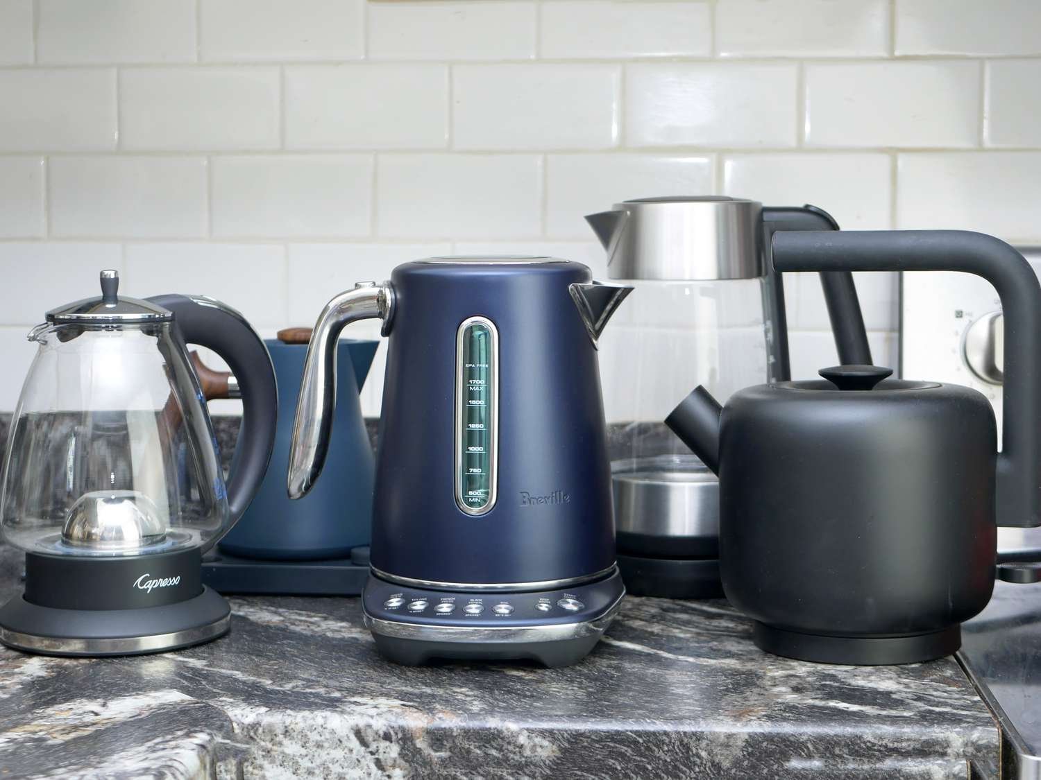 A person adjusting the precise temperature settings on a modern electric kettle base.