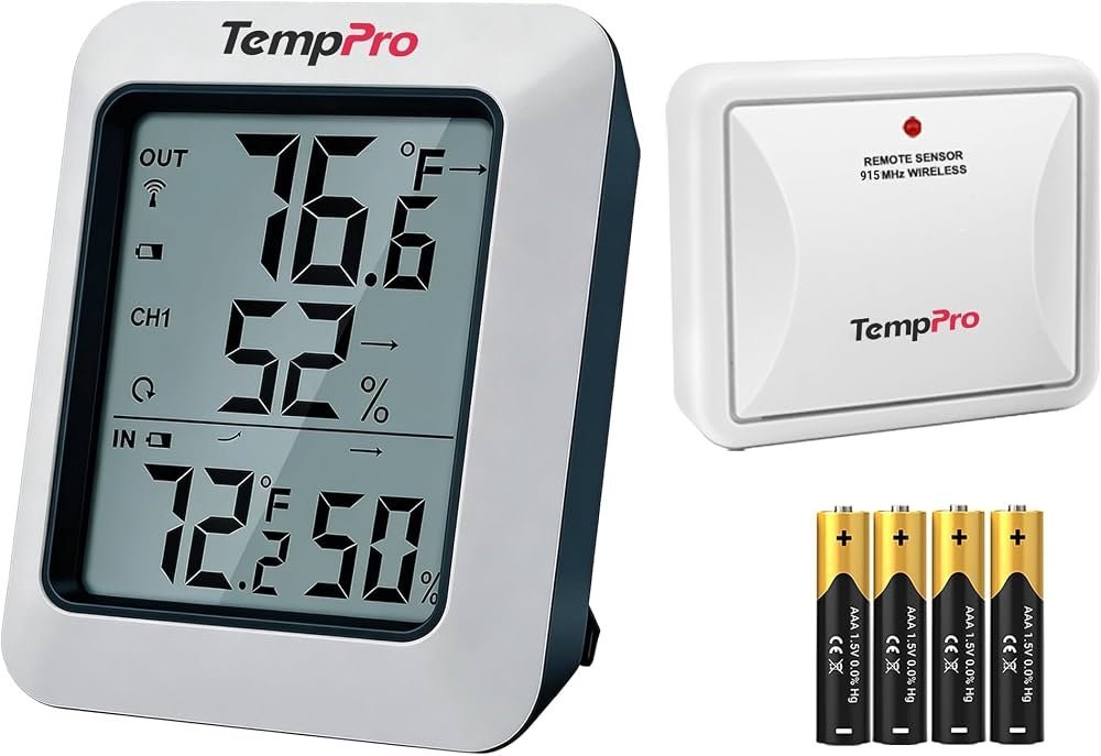 A modern digital outdoor thermometer mounted on a wall with a garden view.