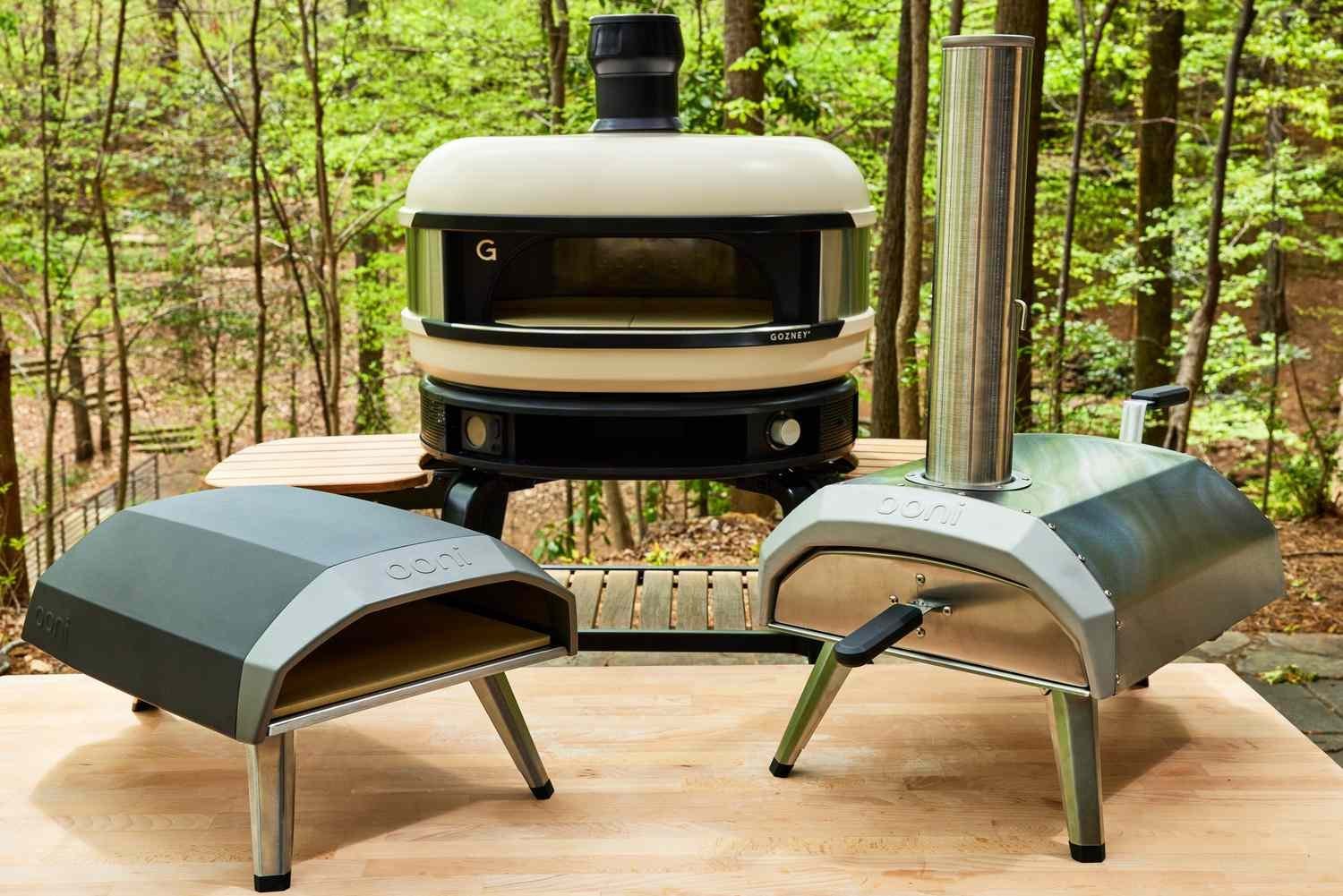 A compact gas-powered outdoor pizza oven sits on a small patio table.