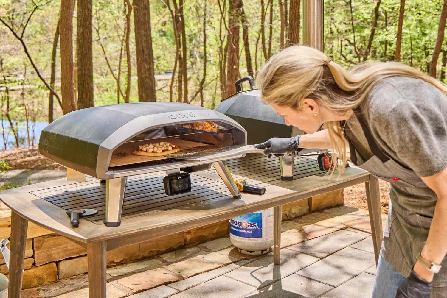 An outdoor pizza oven being cleaned and maintained in a backyard setting.
