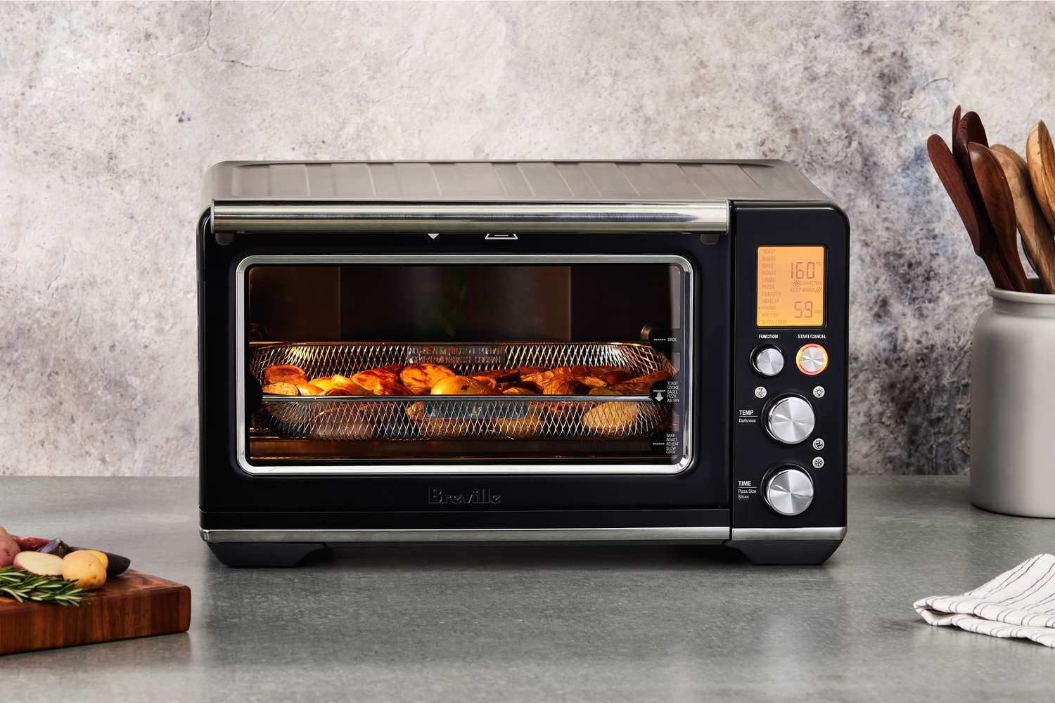 A person uses a thermometer to troubleshoot temperature settings in a compact oven.