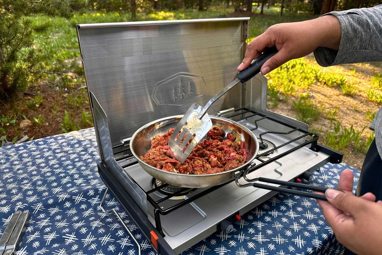 A large portable camping oven set up at a campsite with fresh ingredients.