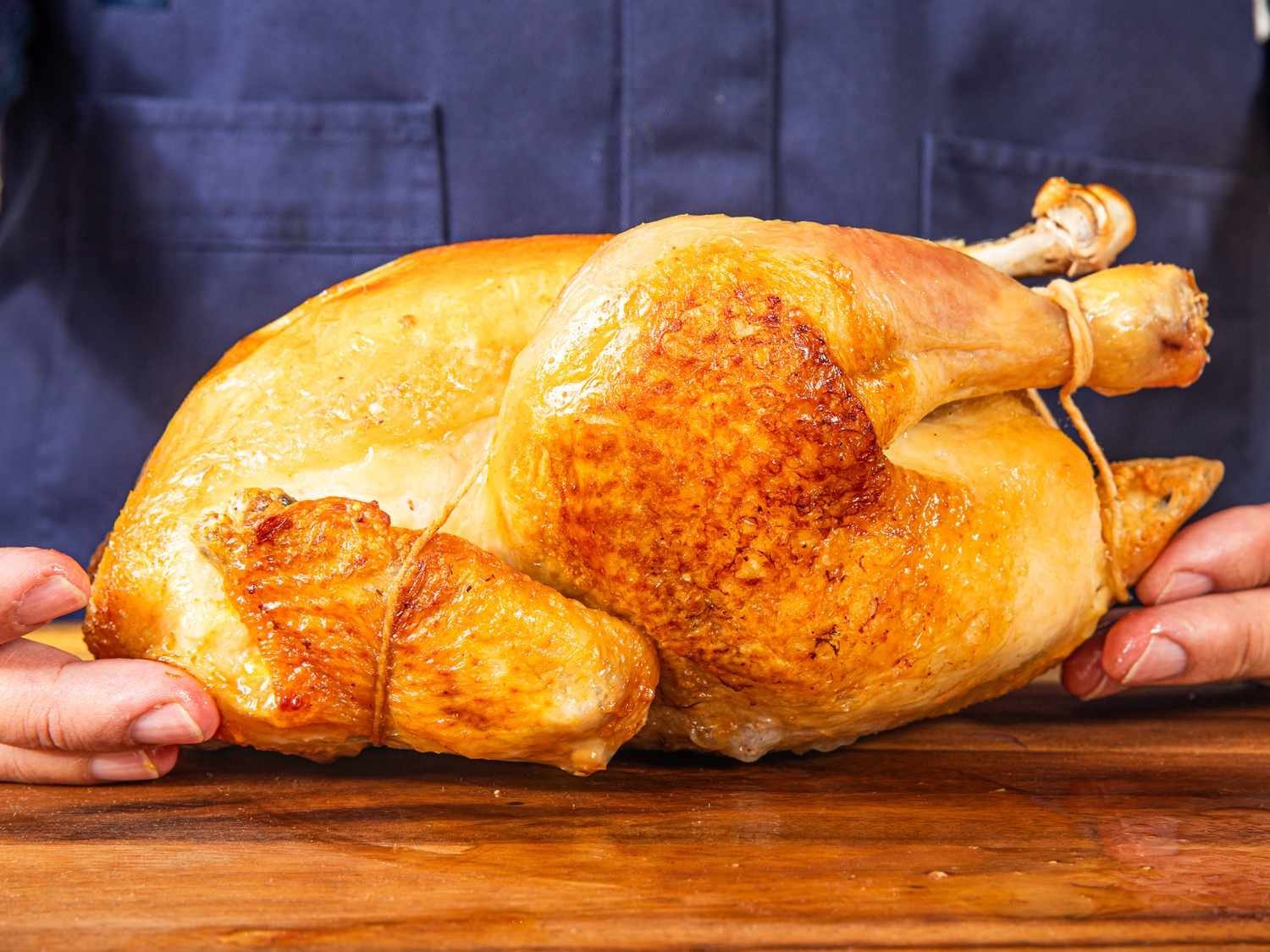 A digital probe thermometer inserted into a raw chicken before choosing the oven temperature.