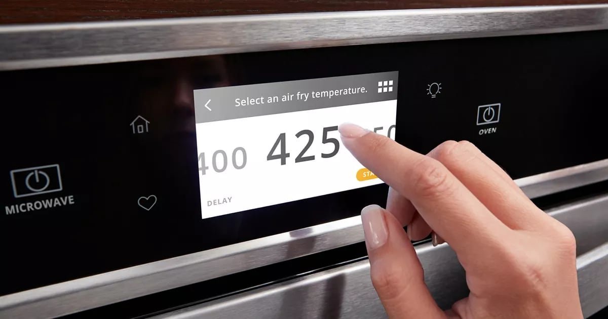 Hands in oven mitts remove a hot dish while managing the oven temperature.