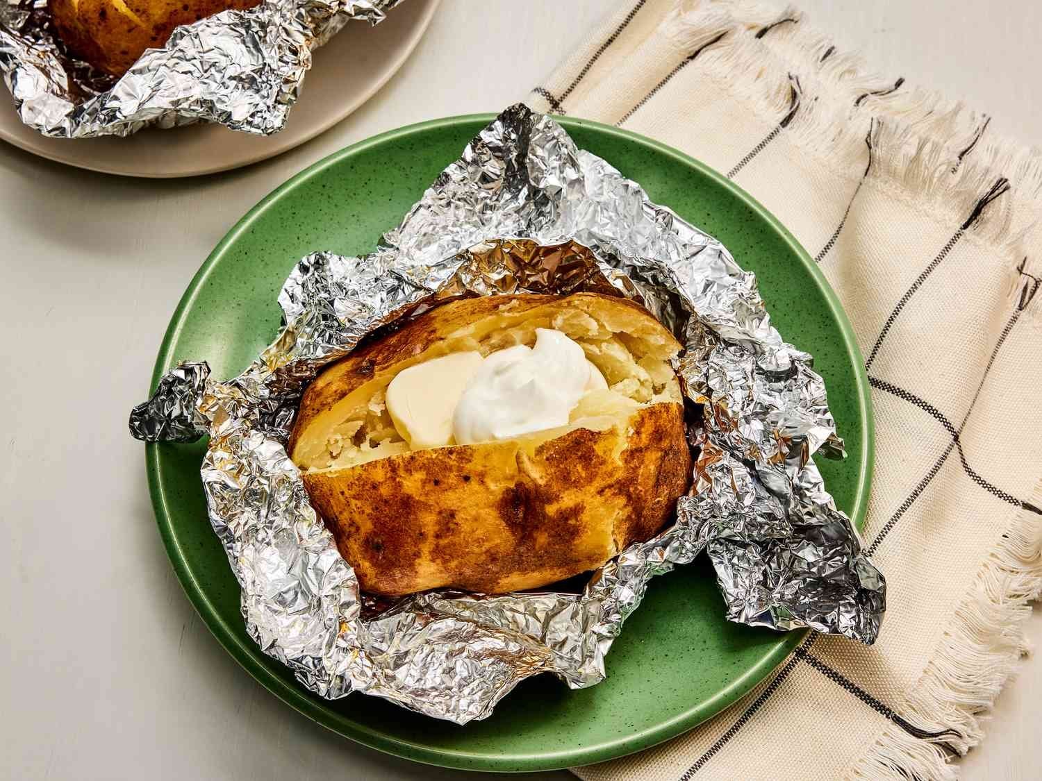 Baked potatoes on a tray showing signs of soggy skin from steam.