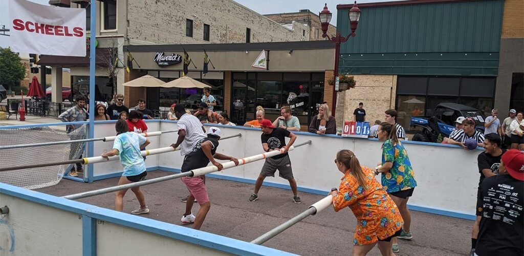 Adults playing human foosball on a sunny lawn with natural lighting