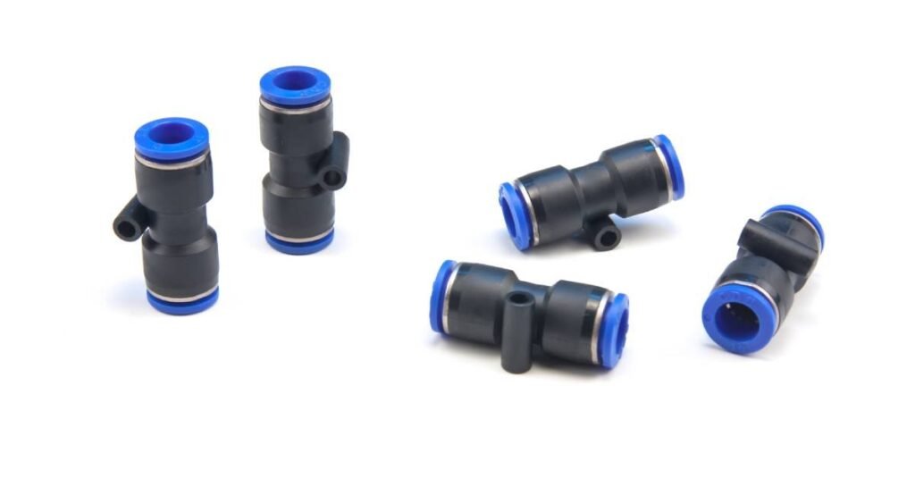 A brass compression fitting and a push-to-connect fitting sitting side-by-side on a workbench.