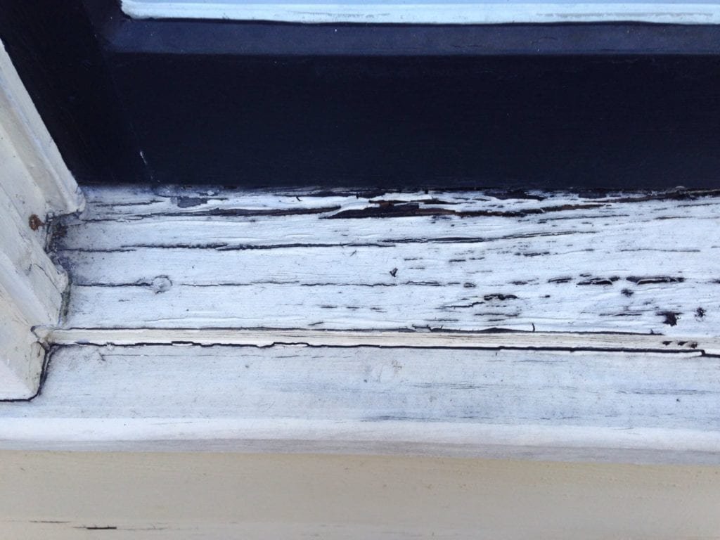 A carpenter measures high-quality wood for a durable window sill replacement project.
