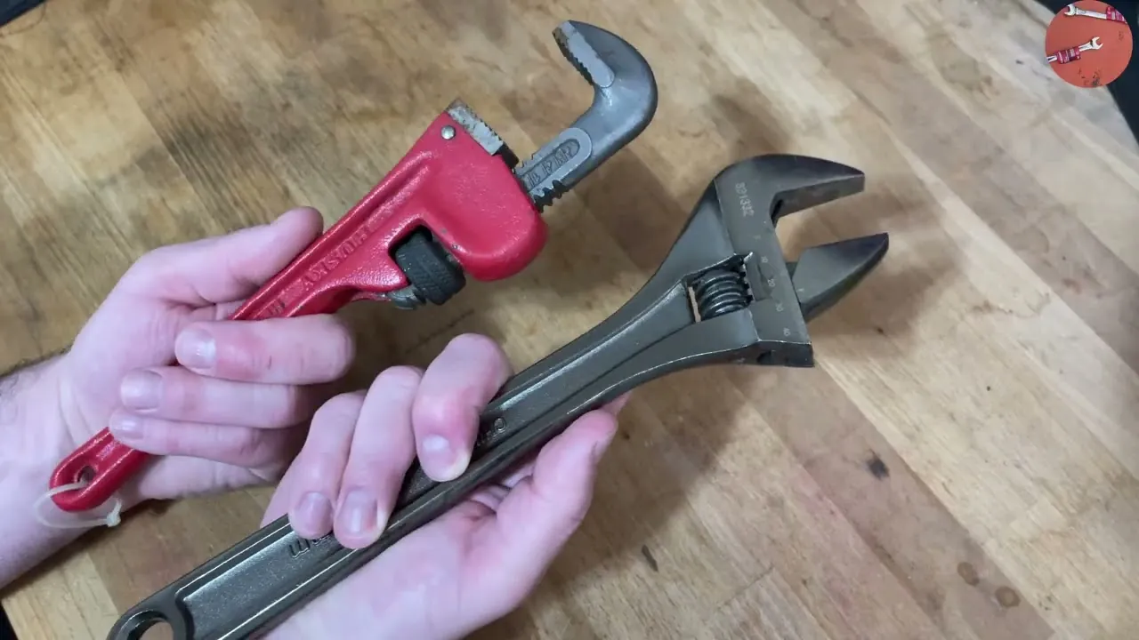 Close-up comparing the serrated jaws of a pipe wrench against an adjustable wrench.