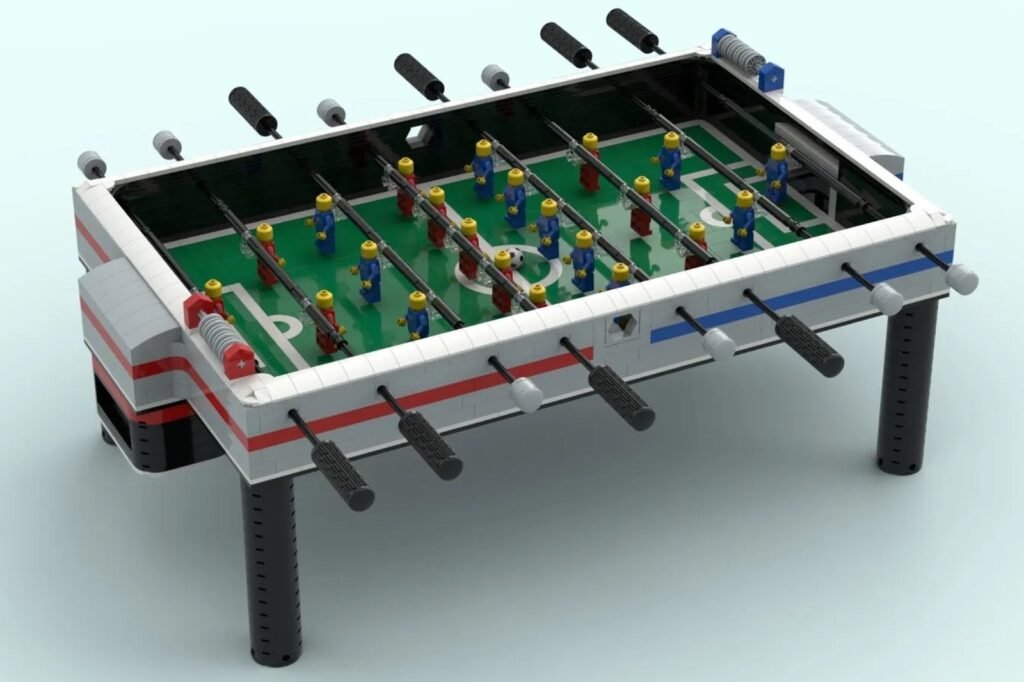 A colorful lego foosball table built from plastic bricks sits on a white desk.