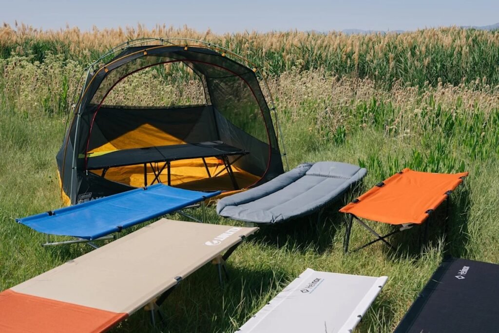 A comfortable camping cot set up inside a well-lit tent ready for sleep.