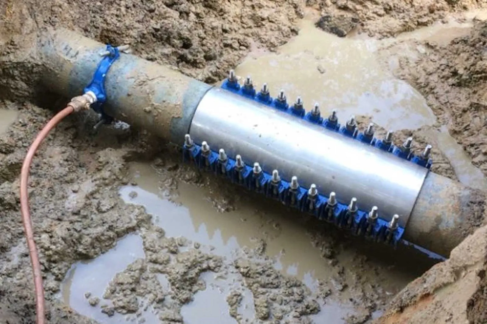 Digital caliper measuring the diameter of a pipe alongside various pipe repair clamps.