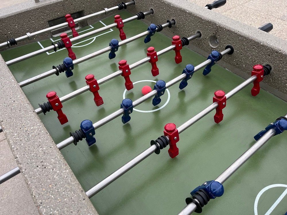 Disassembled foosball table parts and replacement players on a workbench.