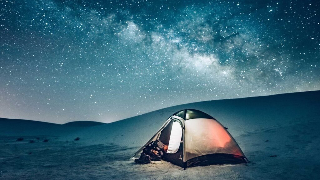 A dome tent with a stargazing window set under a starry night sky
