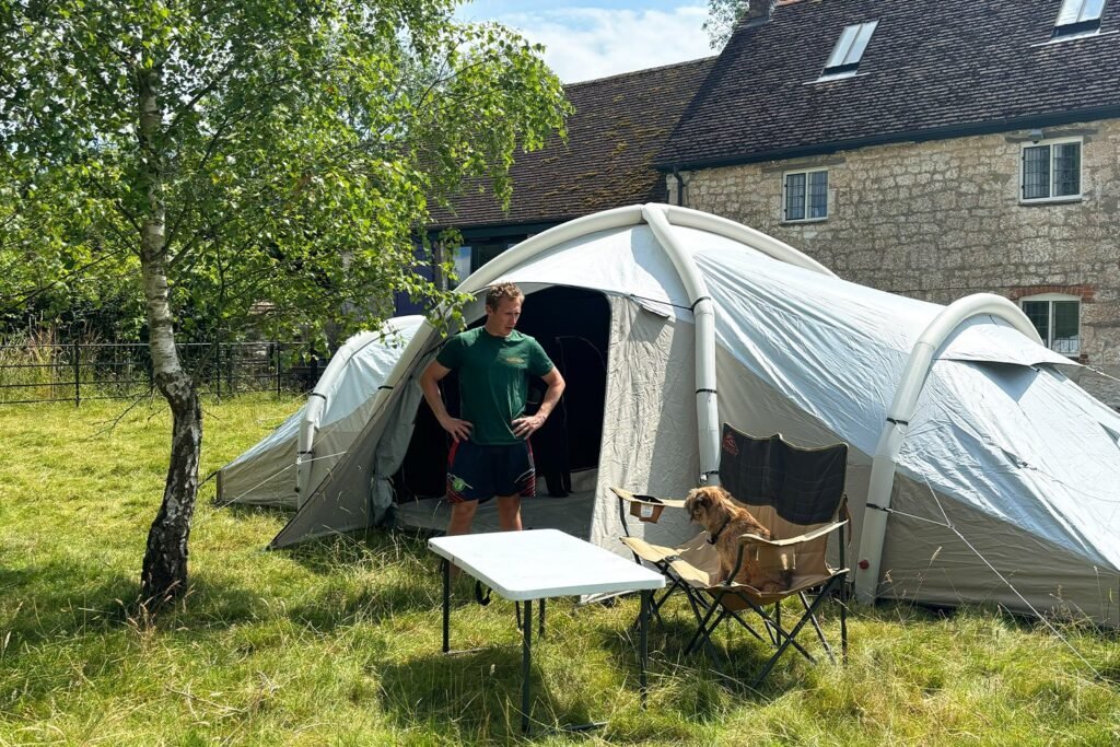 family of six setting up a large tent in a campsite at sunrise