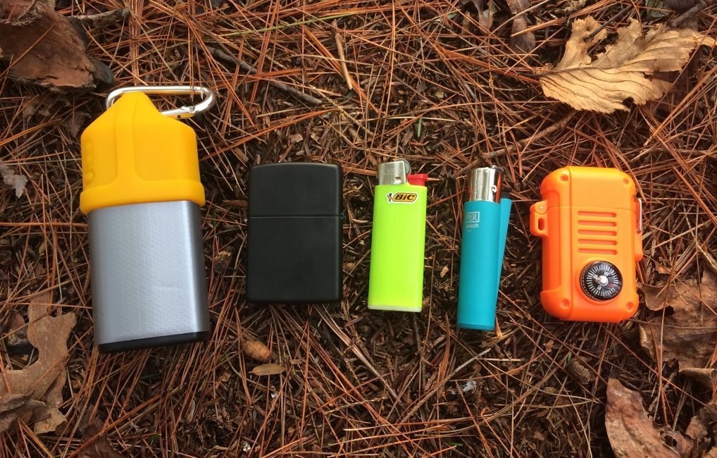 Five durable camping lighters resting on a wooden stump in a forest
