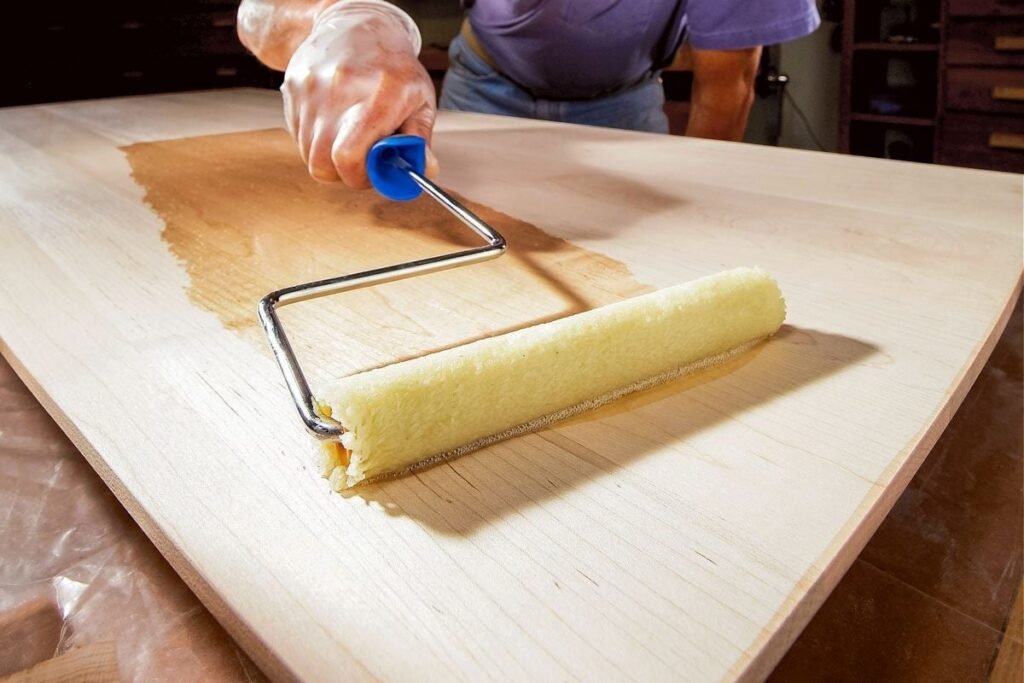 A foam paint roller applying a smooth layer of polyurethane to finished wood.